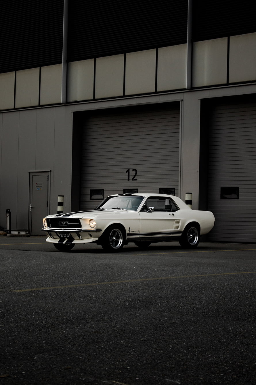 Classic White Ford Mustang Fastback Parked in Industrial Garage Bay HD phone wallpaper