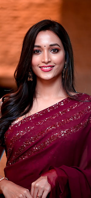 Trisha Krishnan in a stunning maroon sequined saree with traditional jewelry and a warm smile HD phone wallpaper