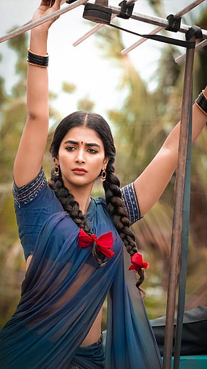 Pooja Hegde in a blue saree with long braids and red ribbons posing outdoors HD phone wallpaper