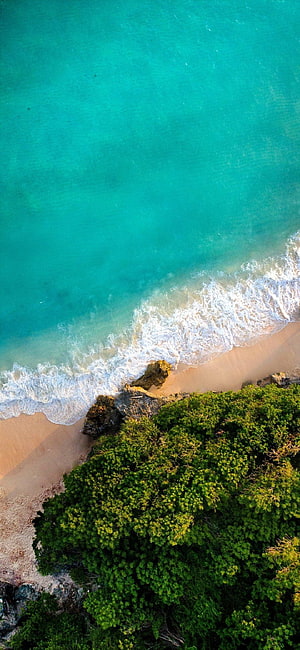 Aerial View of Turquoise Ocean Waves Crashing on Sandy Beach with Lush Green Cliffside HD phone wallpaper