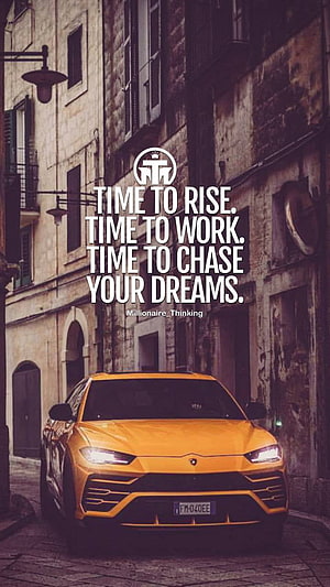 Orange Lamborghini Urus Parked on a Historic European Street with Motivational Quote Overlay HD phone wallpaper