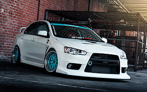 White Mitsubishi Lancer Evolution X with Cyan Wheels Parked Against Brick Wall HD wallpaper