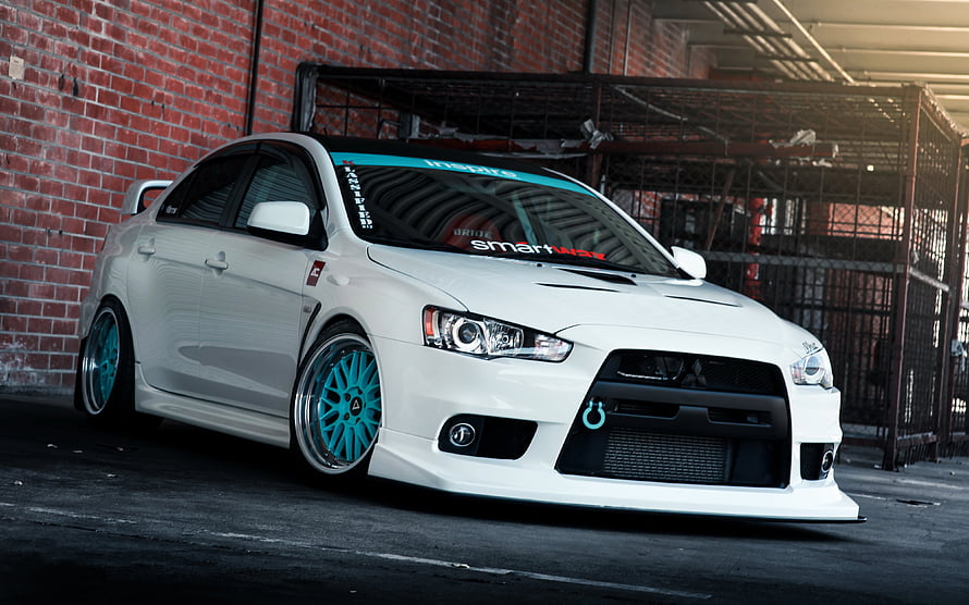 White Mitsubishi Lancer Evolution X with Cyan Wheels Parked Against Brick Wall HD wallpaper
