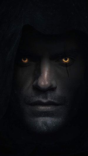 Henry Cavill as The Witcher in a dark hooded portrait with glowing amber eyes HD phone wallpaper