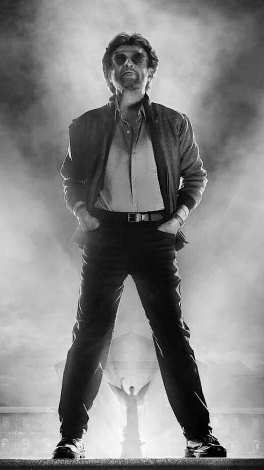 Rajinikanth in a dramatic black and white portrait with smoke and a statue backdrop HD phone wallpaper