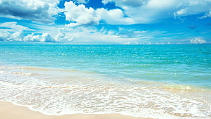 Tropical Beach Landscape With Turquoise Ocean Water And Fluffy White Clouds Under A Bright Blue Sky HD wallpaper