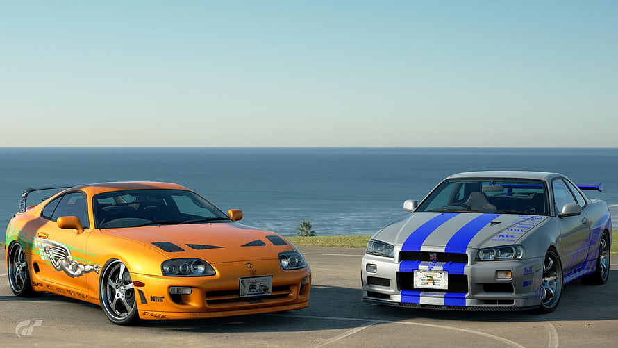 Nissan Skyline GT-R R34 and Toyota Supra RZ parked by the ocean in Gran Turismo HD wallpaper
