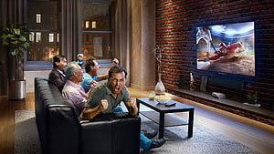 Group of friends cheering while watching a cricket match on a large flat screen TV in a modern living room HD wallpaper