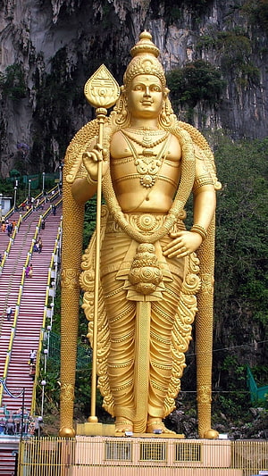 Giant Golden Murugan Statue at Batu Caves with Staircase and Limestone Cliff Background HD phone wallpaper