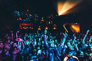 Energetic Crowd at a Live Concert with Dramatic Stage Lighting and Raised Hands HD wallpaper