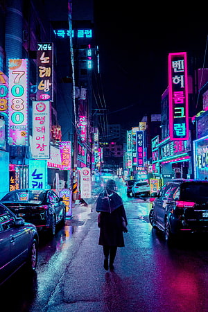 Neon-lit Korean street at night with a lone figure walking under an umbrella, reflecting vibrant pink and blue lights on wet pavement HD phone wallpaper