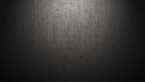 Dark brushed metal texture with vertical grain and soft central spotlight HD wallpaper