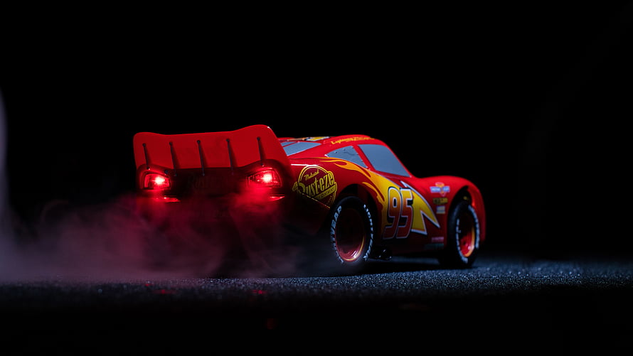 Lightning McQueen 95 Racing Car with Smoke and Red Taillights on Dark Track HD wallpaper