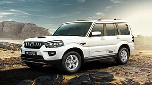 White Mahindra Scorpio SUV parked on rocky desert terrain with dramatic sky backdrop HD wallpaper