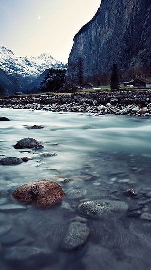 Alpine River Valley with Snow-Capped Peaks and Rustic Cottages HD phone wallpaper