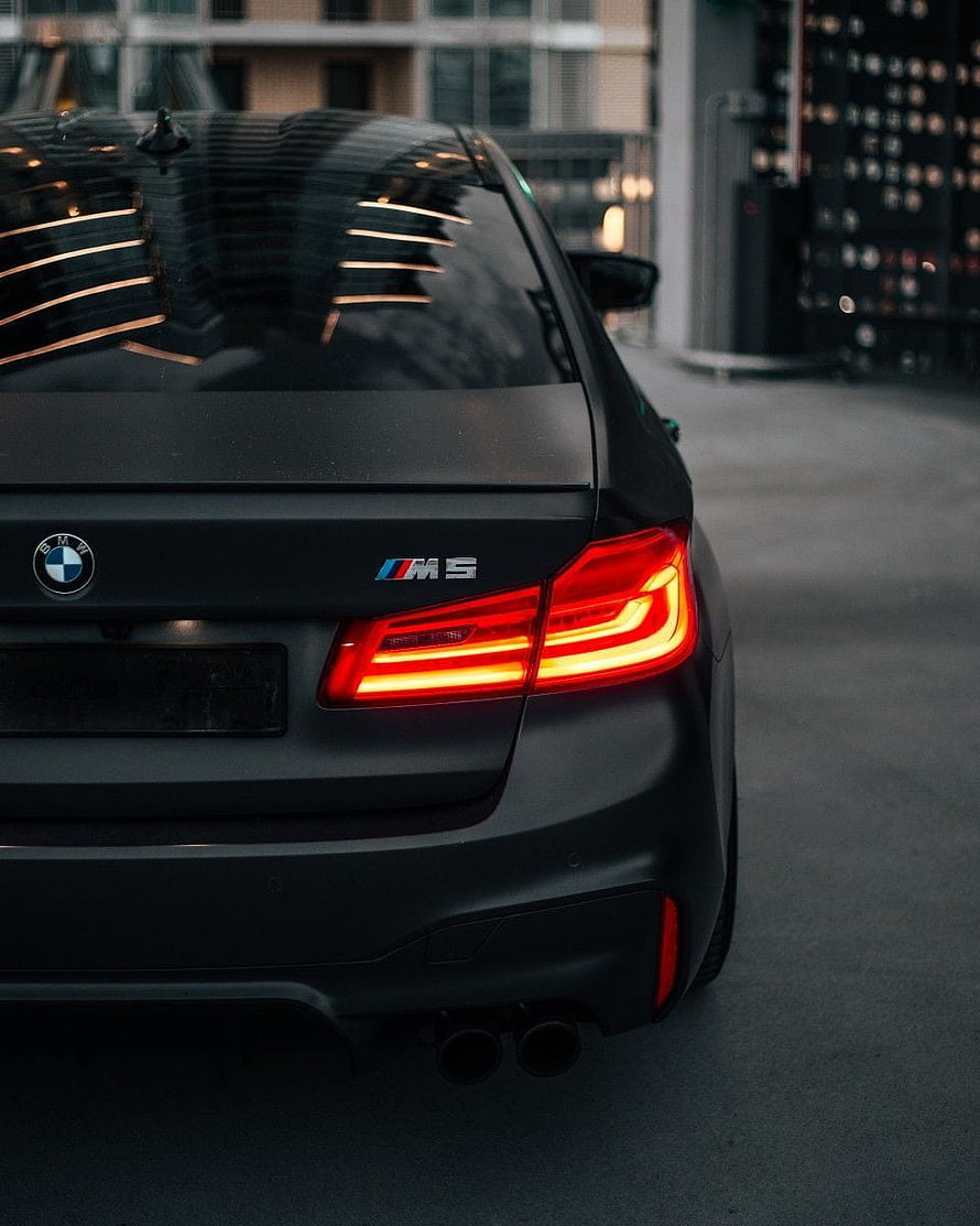 Matte Black BMW M5 Rear View with Glowing LED Tail Lights and Dual Exhaust HD phone wallpaper
