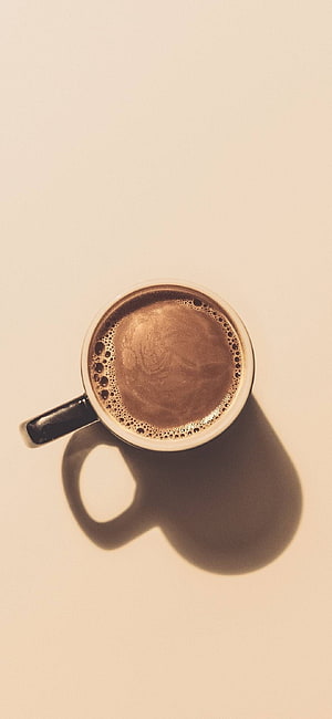 Top View of Frothy Coffee in a White Mug with Strong Shadow on Beige Background HD phone wallpaper