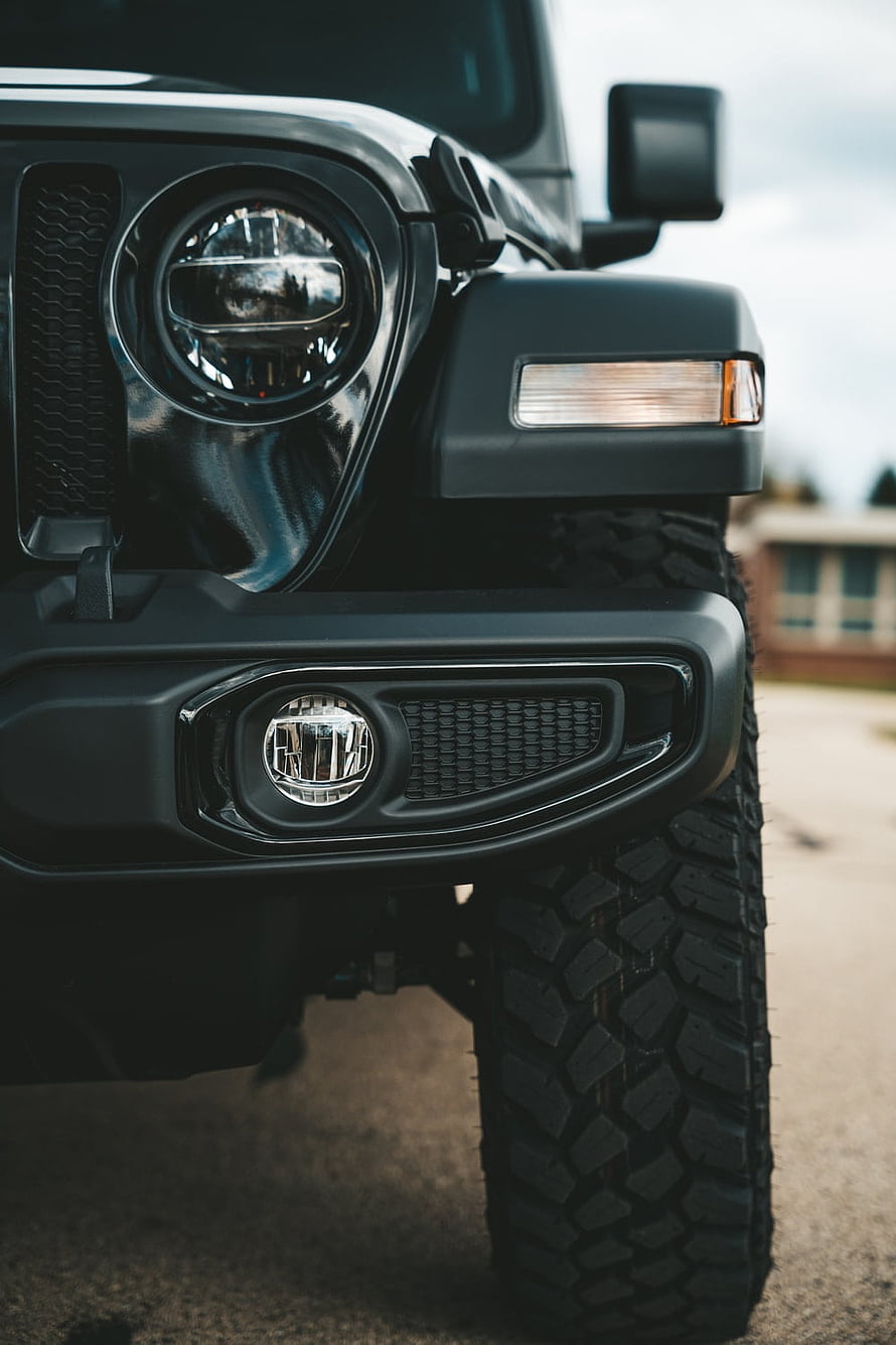 Close-Up of Black Jeep Wrangler Front Headlight and Off-Road Tire Detail HD phone wallpaper