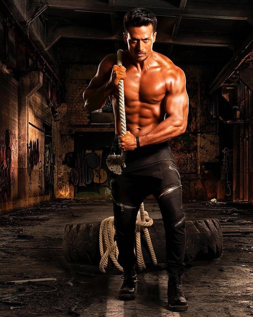 Tiger Shroff shirtless fitness portrait gripping a rope in a gritty urban gym setting HD phone wallpaper