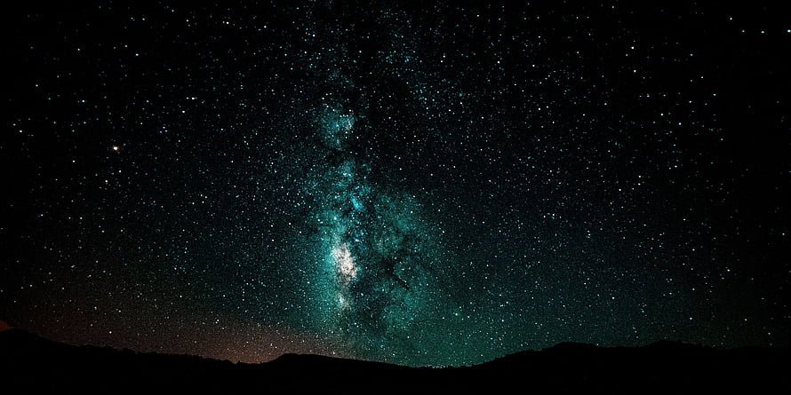 Milky Way Galaxy Arching Over a Dark Mountain Silhouette in a Star-Filled Night Sky HD wallpaper