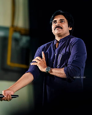 Pawan Kalyan in a navy blue shirt gesturing on stage with a microphone HD phone wallpaper