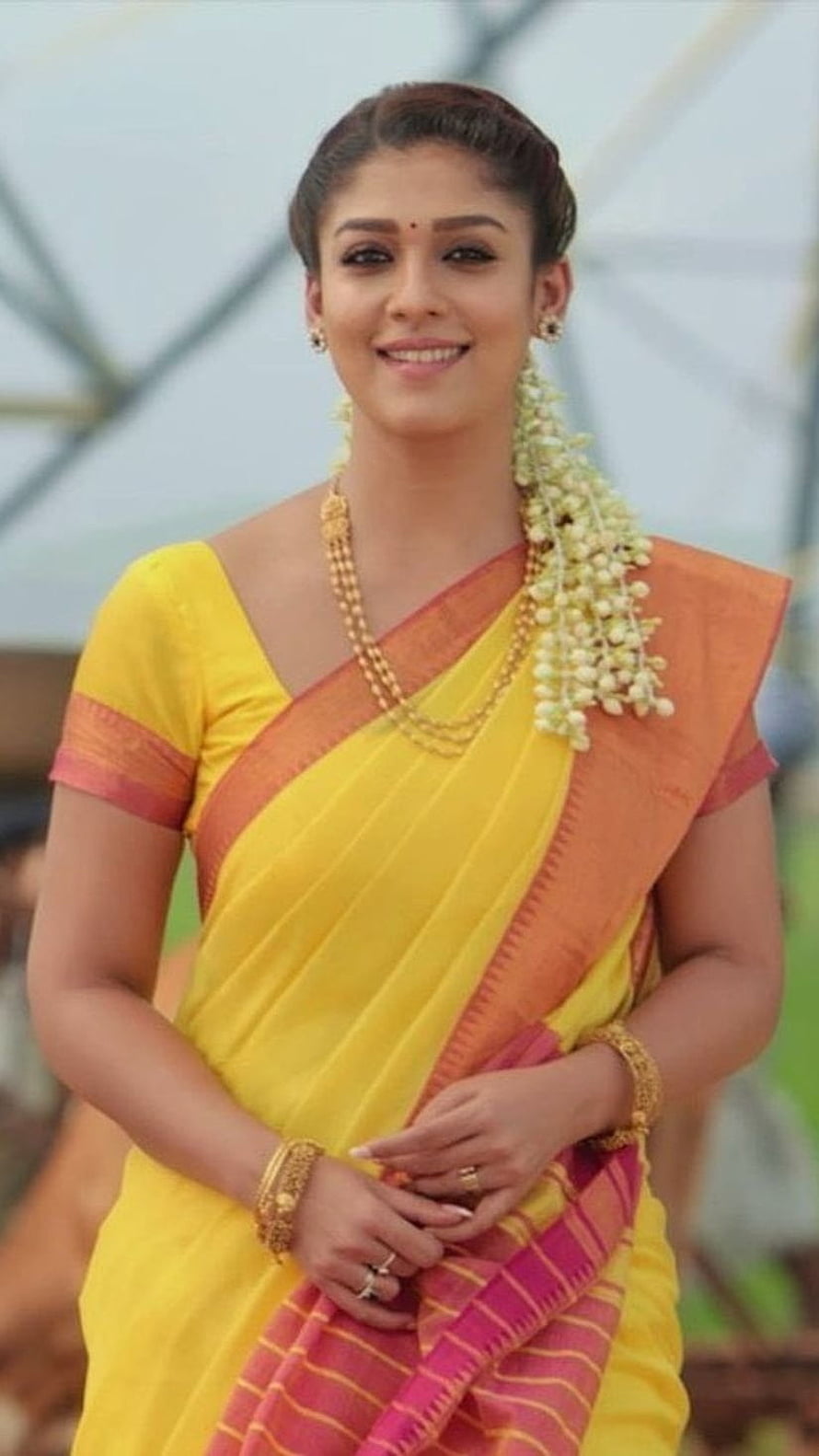 Nayanthara in a vibrant yellow and orange silk saree with traditional gold jewelry and jasmine garland HD phone wallpaper