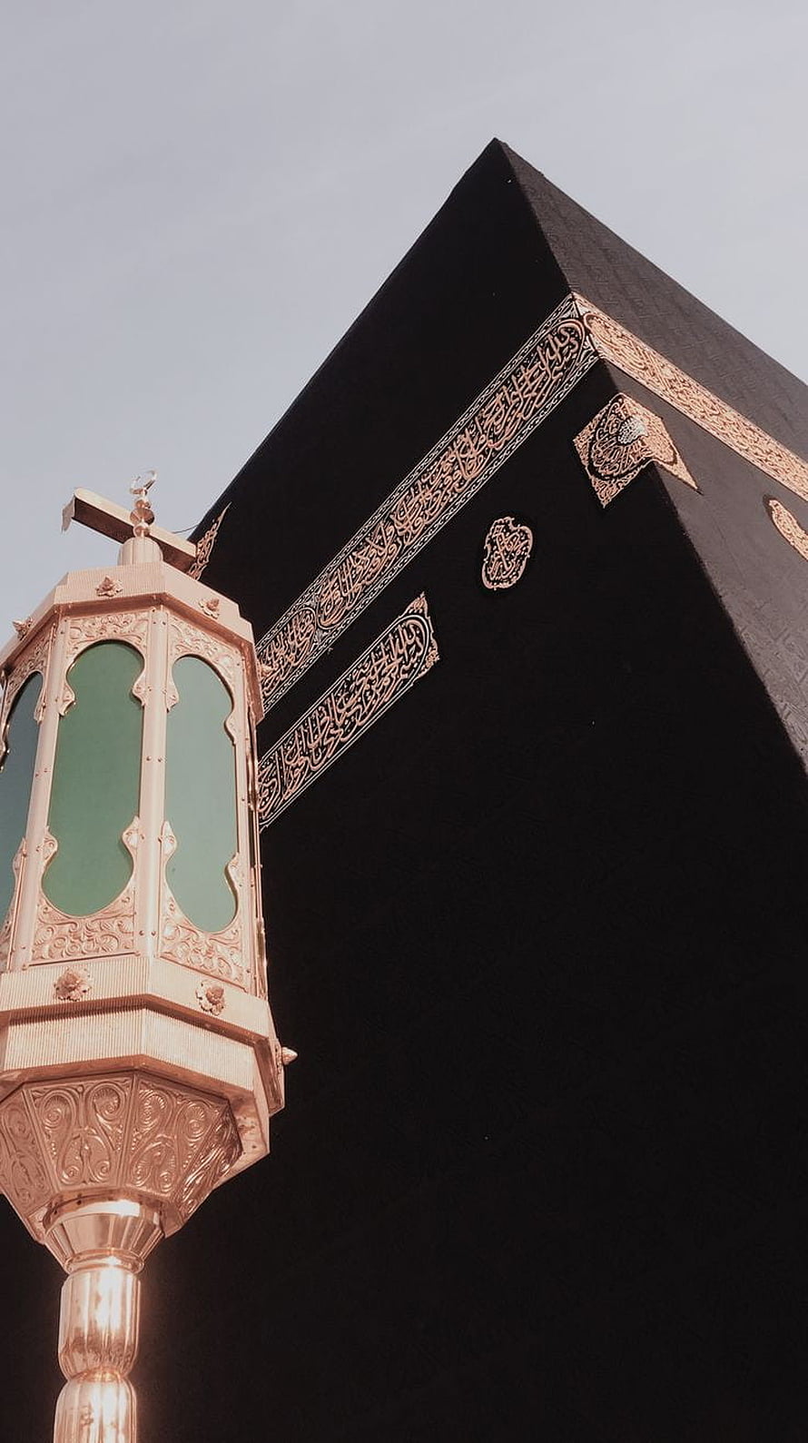Kaaba in Mecca with ornate golden lantern and Arabic calligraphy against a clear sky HD phone wallpaper