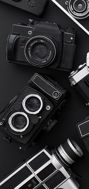 Vintage Film Cameras and Lenses Arranged on a Dark Surface HD phone wallpaper