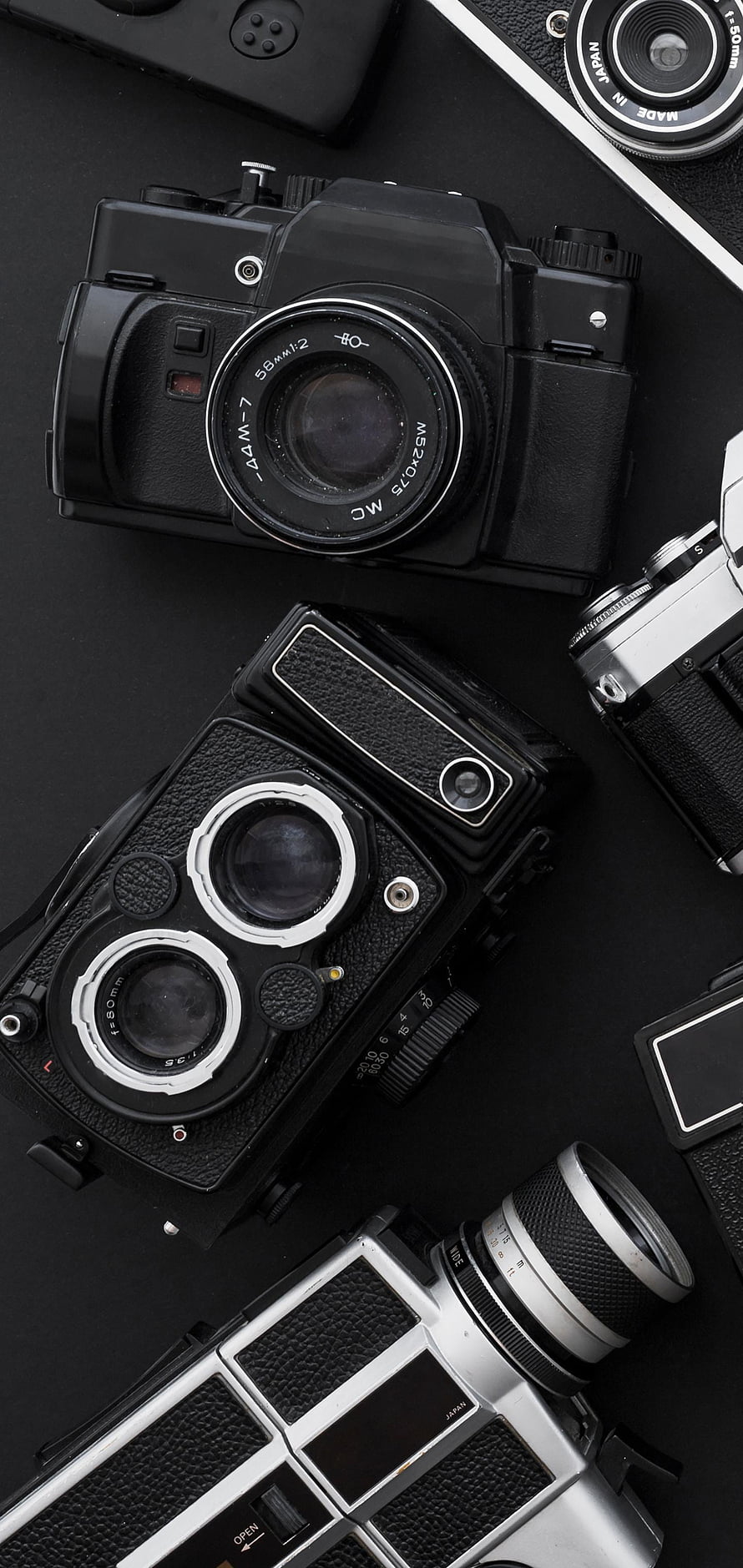 Vintage Film Cameras and Lenses Arranged on a Dark Surface HD phone wallpaper