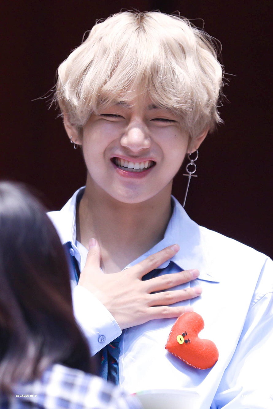 V from BTS smiling with hand on chest wearing a white shirt and red heart pin HD phone wallpaper