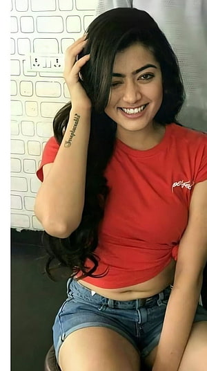 Sai Pallavi smiling in a red crop top and denim shorts with long dark hair HD phone wallpaper