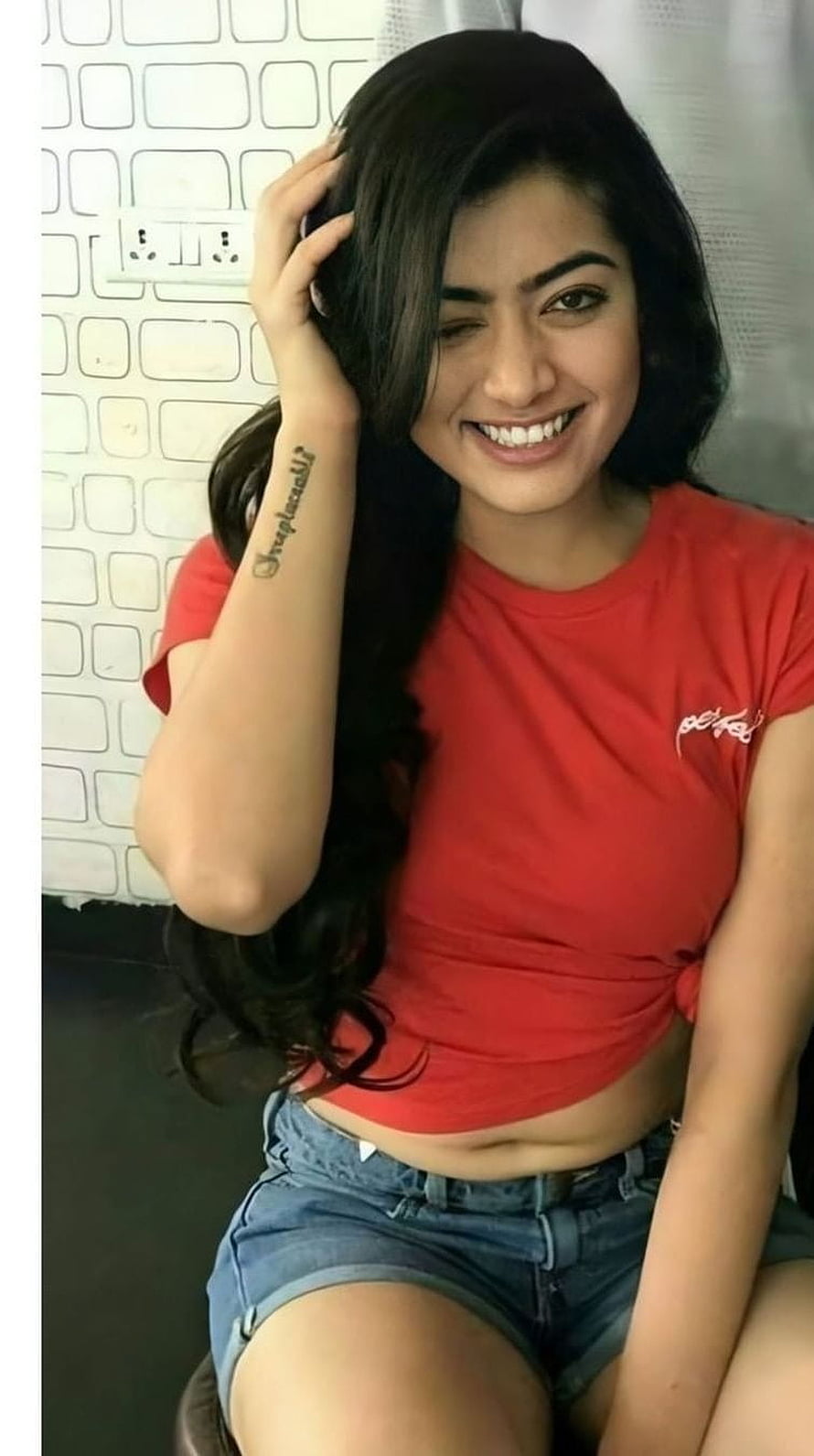 Sai Pallavi smiling in a red crop top and denim shorts with long dark hair HD phone wallpaper