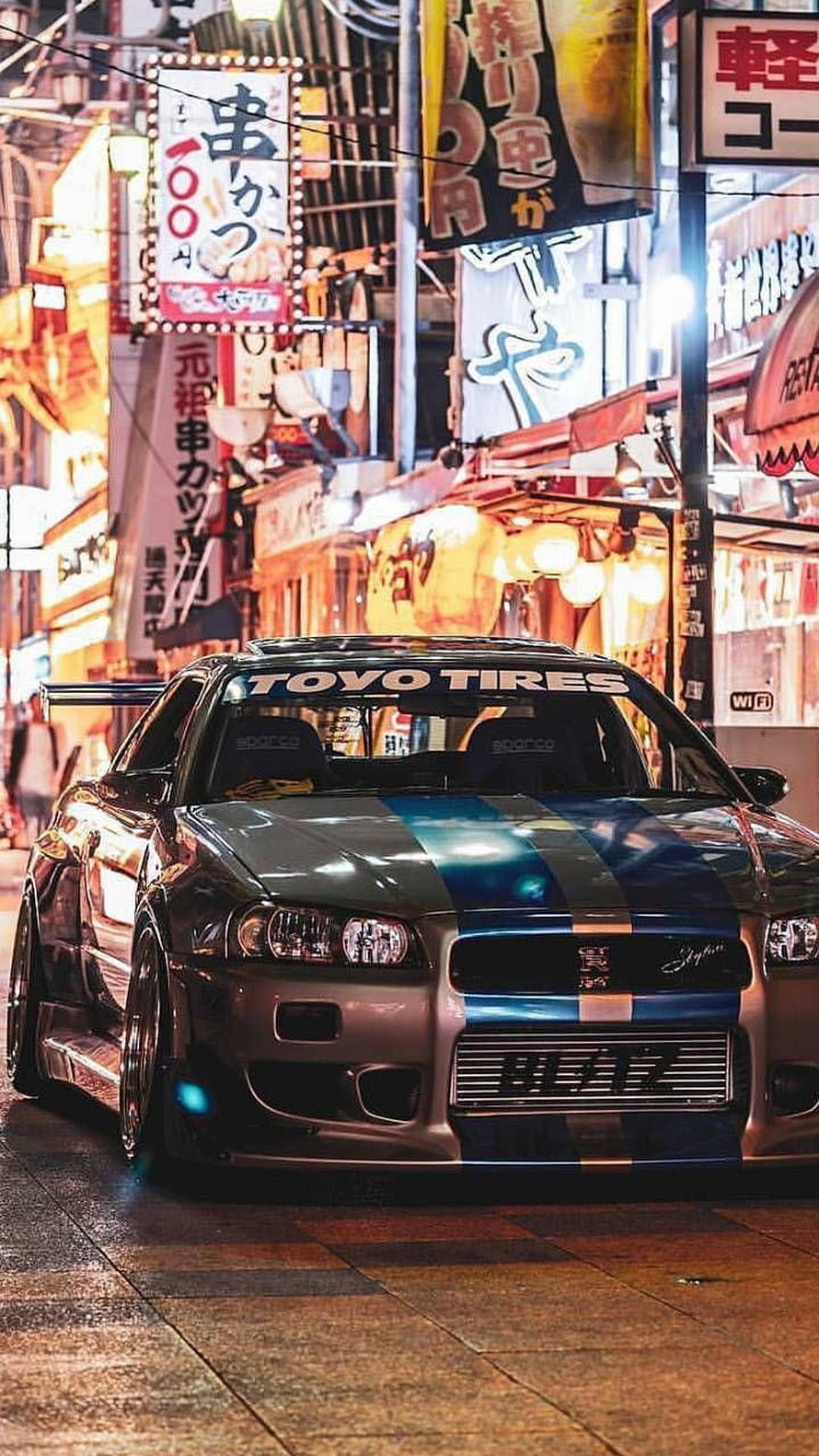 Nissan Skyline GT-R R34 in Japanese Street Scene with Neon Signs HD phone wallpaper