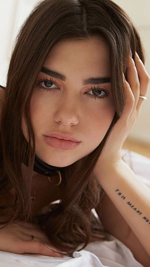Portrait of a woman with long brown hair, a black choker, and a forearm tattoo resting her head on her hand, Dua Lipa HD phone wallpaper