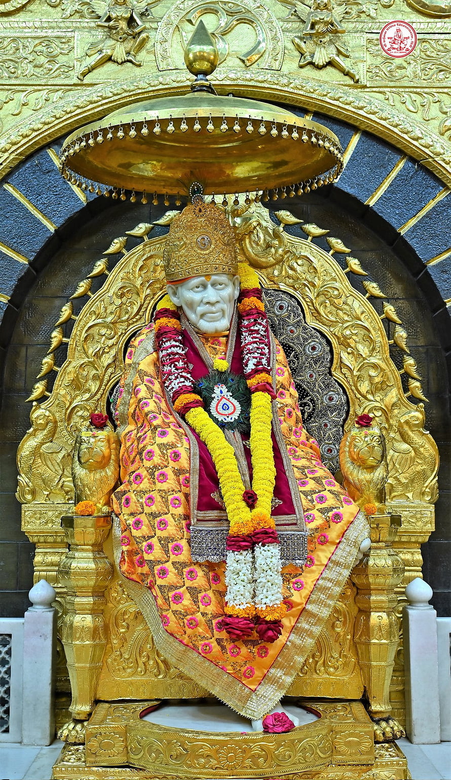 Golden Statue of Sai Baba Seated on Ornate Throne with Flower Garlands HD phone wallpaper