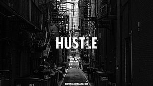 Black and white urban alleyway with fire escapes and motivational hustle text overlay HD wallpaper