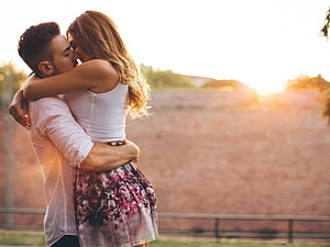 Romantic couple embracing and kissing in warm golden hour sunlight HD wallpaper