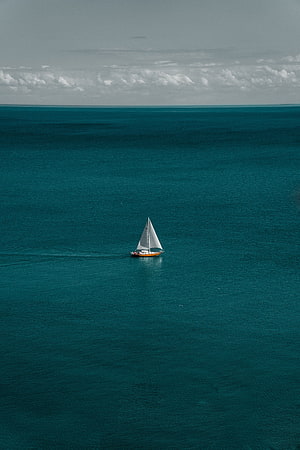 Lone Sailboat Drifting on Vast Teal Ocean Under Overcast Sky HD phone wallpaper