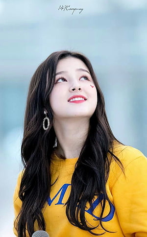 Nancy from Momoland in a yellow sweatshirt with long dark hair and a warm smile HD phone wallpaper
