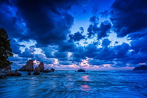 Dramatic Coastal Sunset with Stormy Clouds and Rocky Shoreline HD wallpaper