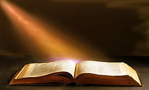 Open Bible with Divine Light Beam and Warm Golden Glow on Dark Background HD wallpaper