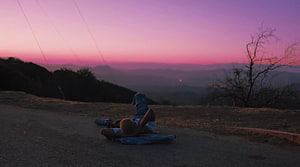 Jaden Smith Reclining on a Hilltop Road at Sunset with a Vibrant Pink Sky HD wallpaper