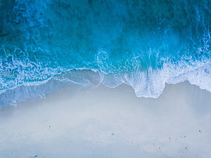 Aerial View of Turquoise Ocean Waves Crashing on White Sandy Beach HD wallpaper