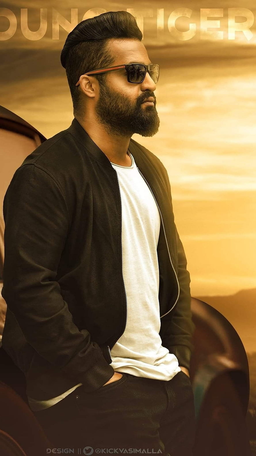 NTR in Sunglasses and Black Bomber Jacket with Golden Desert Sky Background HD phone wallpaper