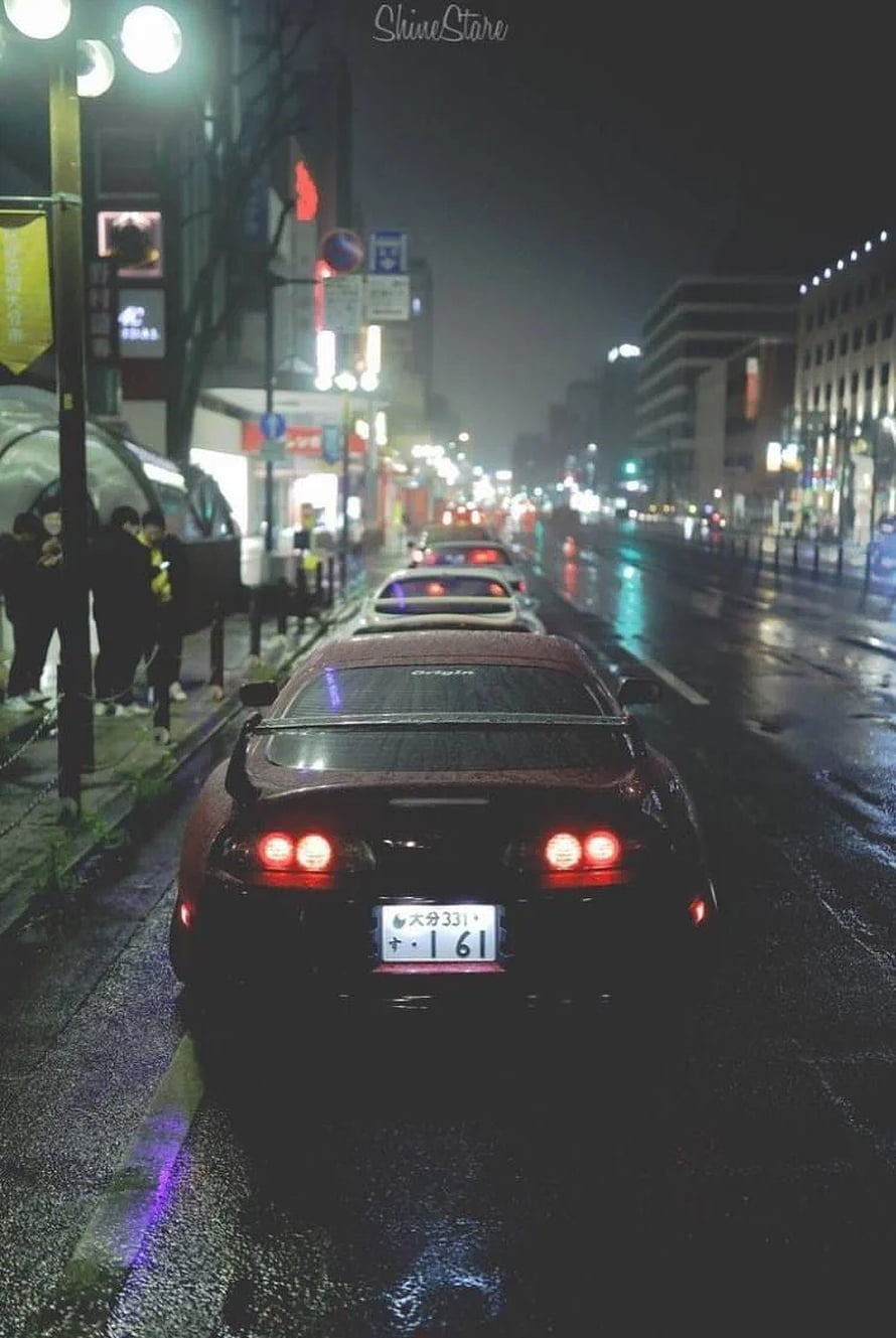 Rear View of a Black Nissan Skyline GT-R on a Rainy Japanese City Street at Night HD phone wallpaper