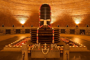 Sacred Shiva Lingam in a Dimly Lit Temple with Oil Lamps and Flower Offerings HD wallpaper
