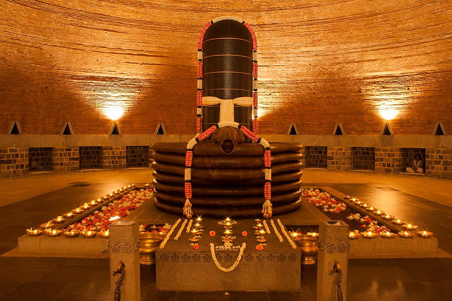 Sacred Shiva Lingam in a Dimly Lit Temple with Oil Lamps and Flower Offerings HD wallpaper