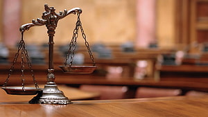 Scales of Justice on Wooden Table in Blurred Courtroom Background HD wallpaper