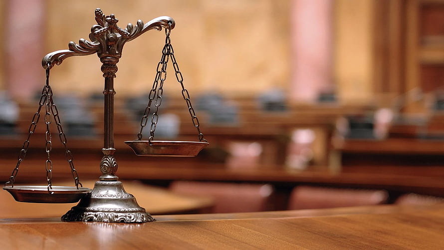 Scales of Justice on Wooden Table in Blurred Courtroom Background HD wallpaper