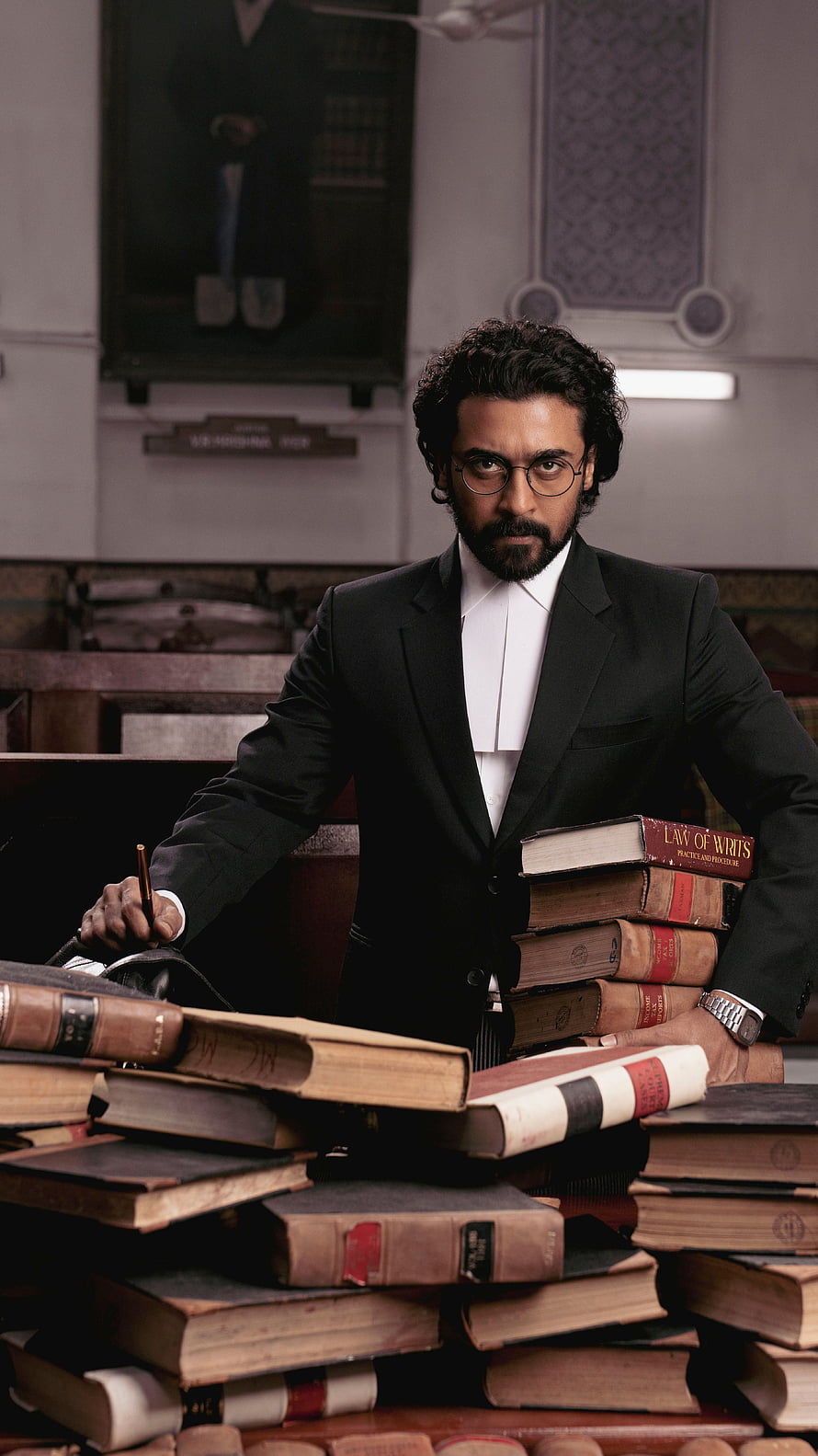 Aishwarya Rai Bachchan in a formal black suit with a stack of law books in a courtroom setting HD phone wallpaper